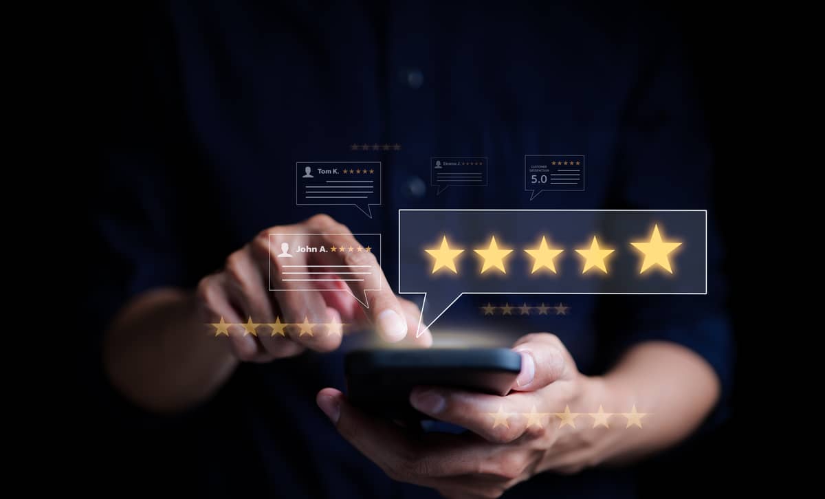 A person's hands holding a phone that shows multiple 5-star reviews